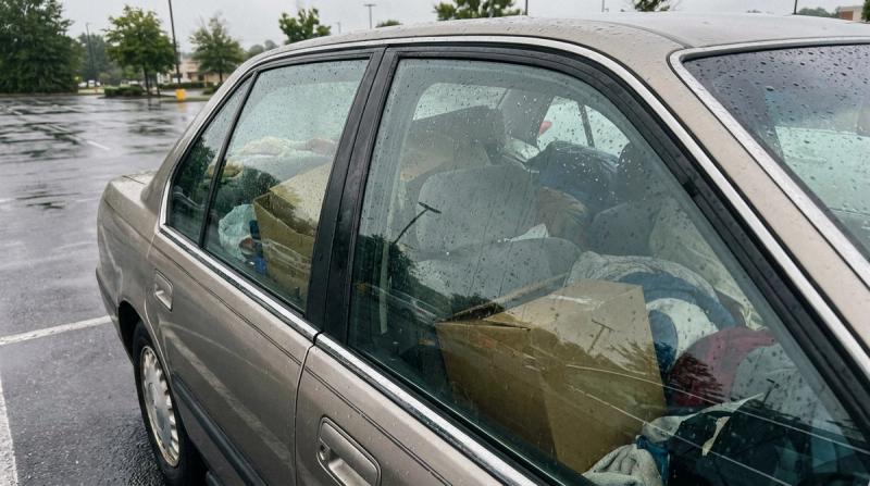 The back seat of a car packed with boxes and belongings seen through the window on an overcast morning