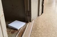 A small square of folded lined exercise paper resting inside an old metal school locker