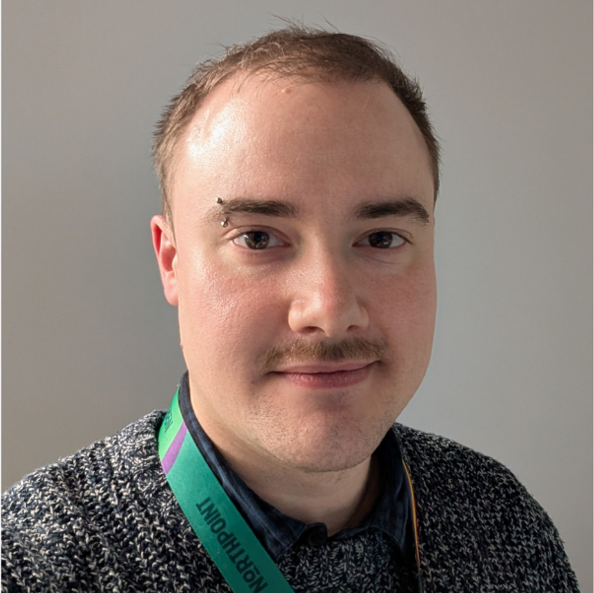 Sam, wearing a Northpoint lanyard, photographed against a plain grey wall.