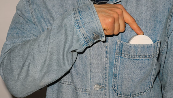 Person reaching for a nicotine pouch from a jacket pocket
