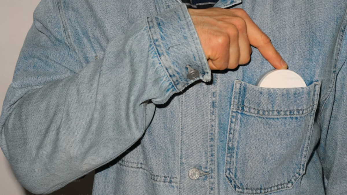 Person reaching for a nicotine pouch from a jacket pocket