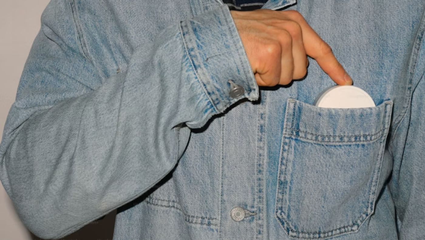 Person reaching for a nicotine pouch from a jacket pocket