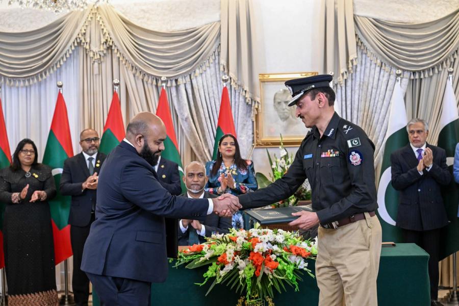A Maldivian official exchanges a folder with a uniformed Pakistani police officer.