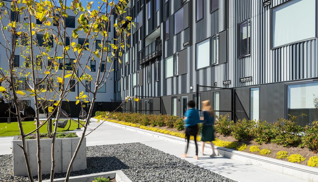People walking in the steelcote flats amenity deck courtyard with greenery on both sides in st louis missouri.