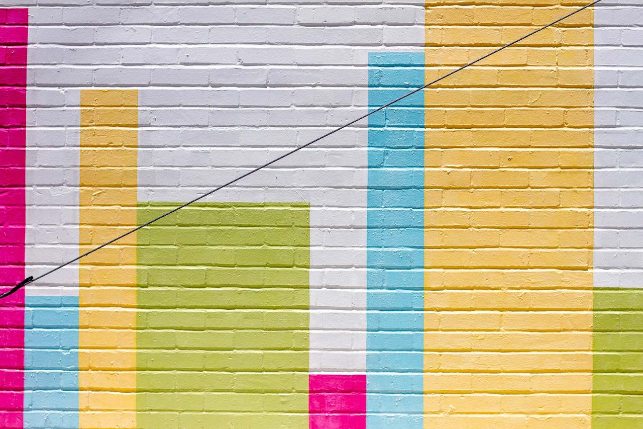 Pink, blue, green, and yellow painted brick wall at the score art and music promenade grand center st louis missouri done by arbolope studio