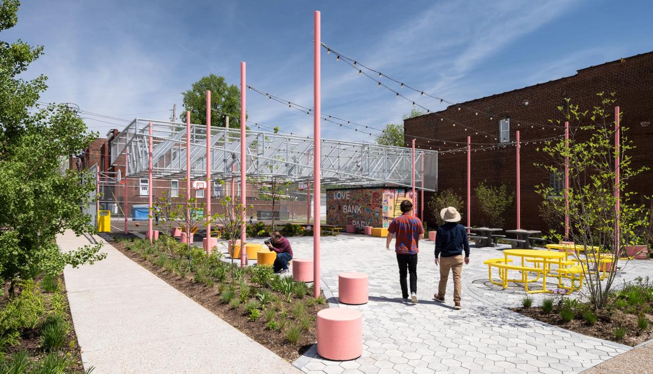 Two men stroll through the center of love bank park on cherokee street while another person bends down to take photos of the;landscaping designed by arbolope studio of st louis missouri.