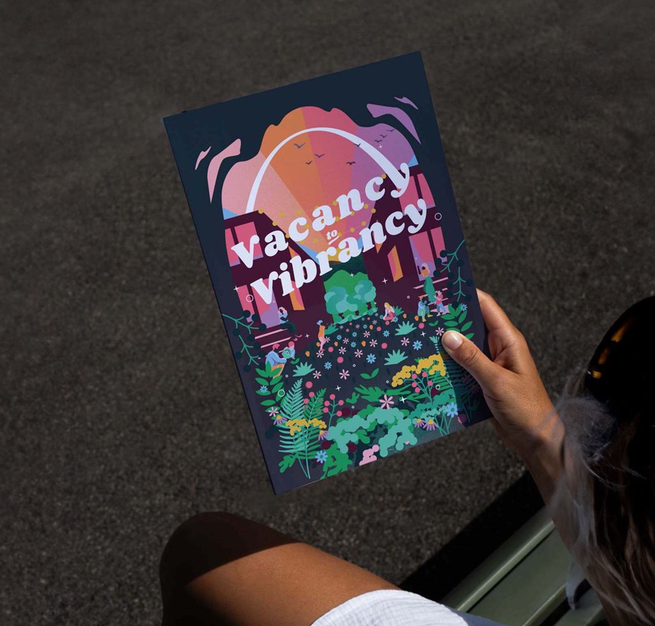 Person on a bench holding the vacant lots toolkit: vacancy to vibrancy by arbolope studio of st louis missouri.