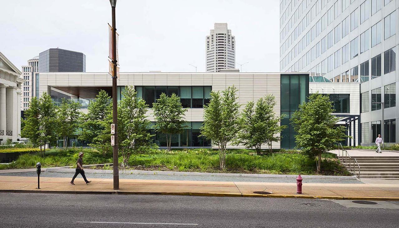 Person wearing a hat walking down the sidewalk on north broadway in st louis missouri. New courtyard redesigned by arbolope studio.