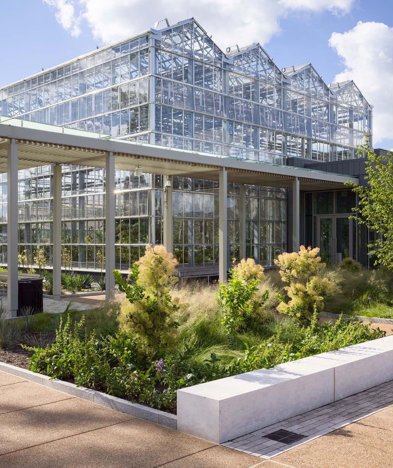 Planting beds form multiple green patches throughout the entrance at the new jack c taylor visitor center at the missouri botanical gardens in st louis.