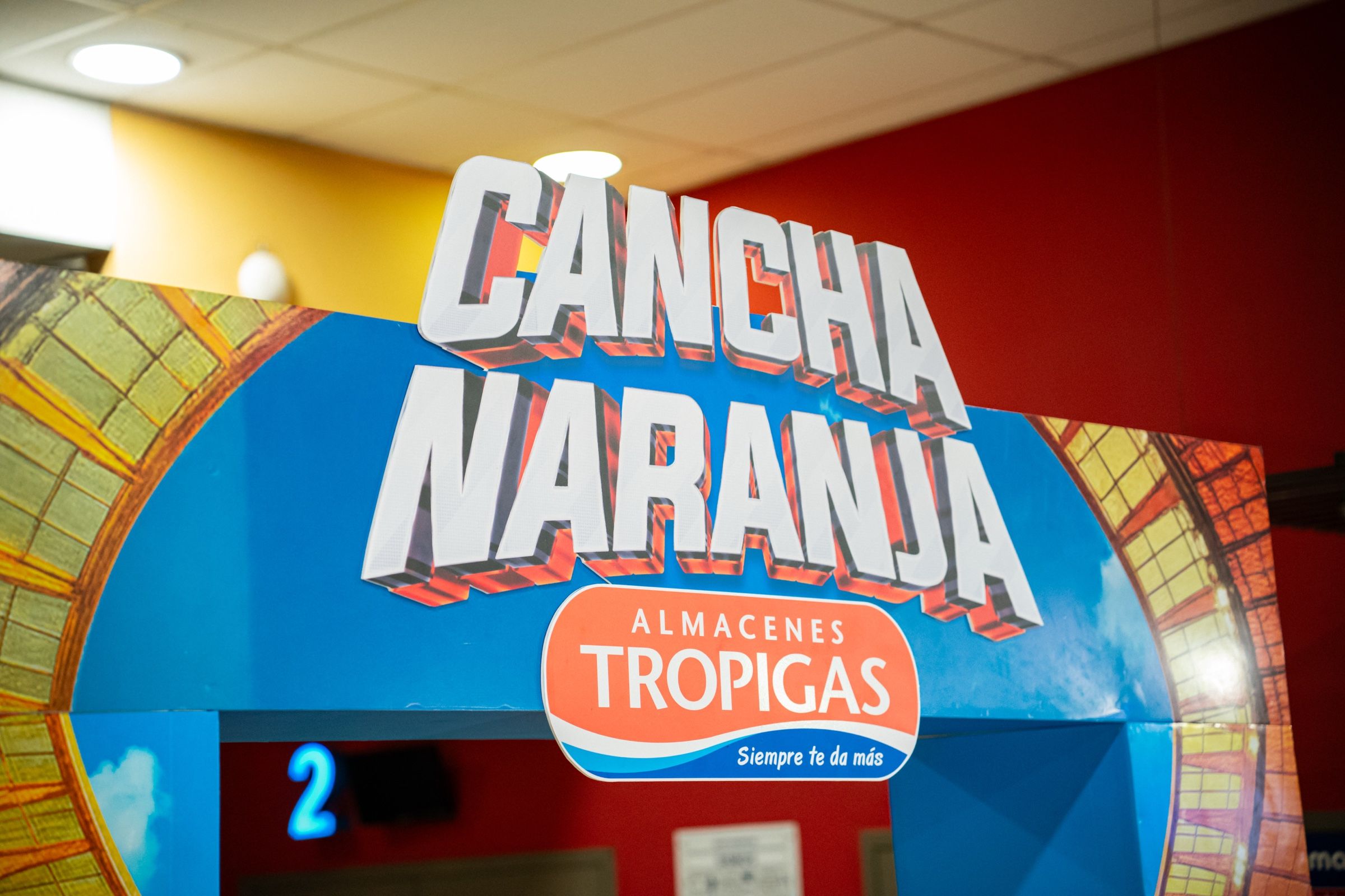 Arco de entrada de la activación Cancha Naranja, con el logo de Almacenes Tropigas.