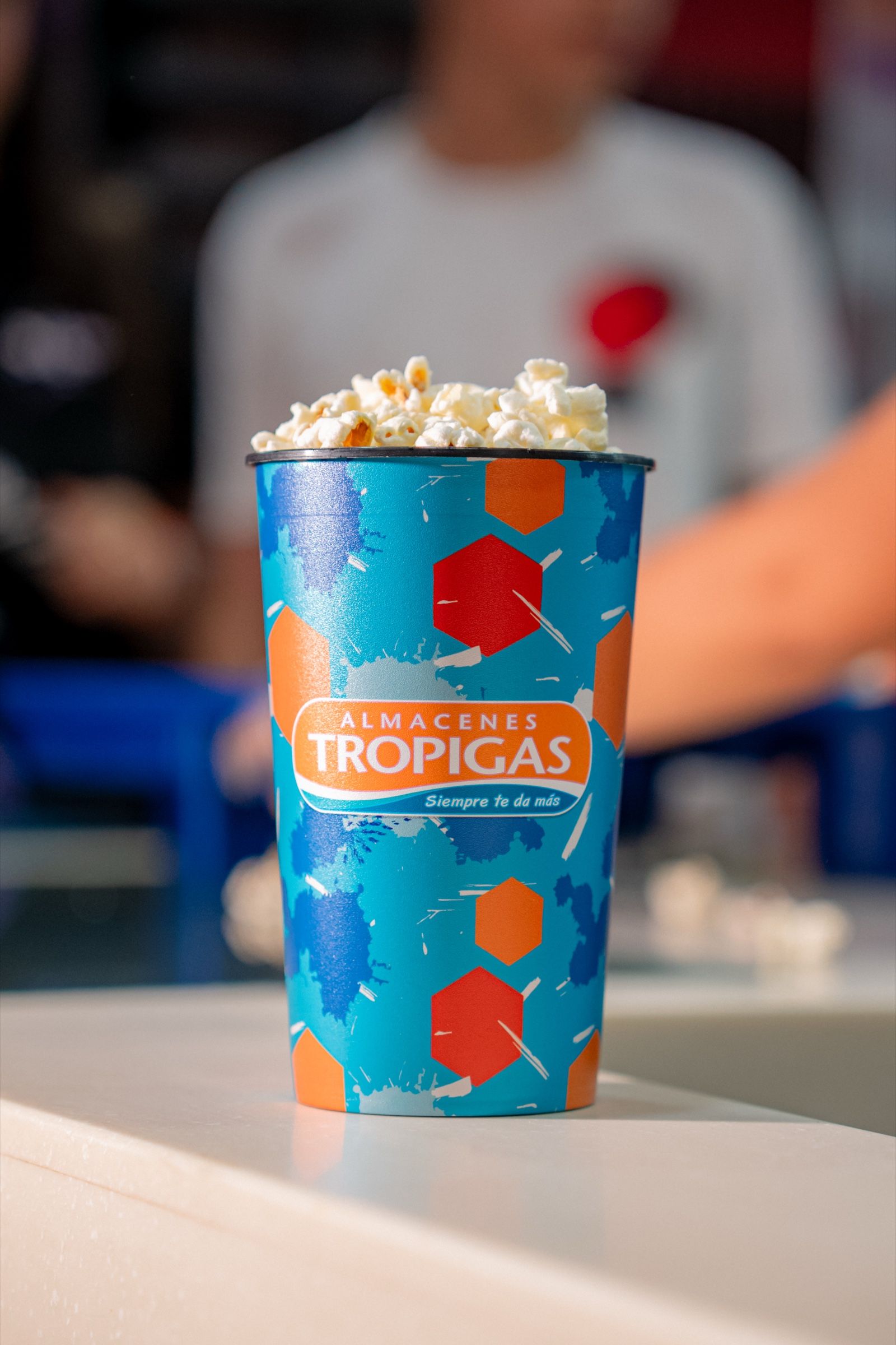 Vaso de palomitas de Cancha Naranja sobre el mostrador de la dulcería.