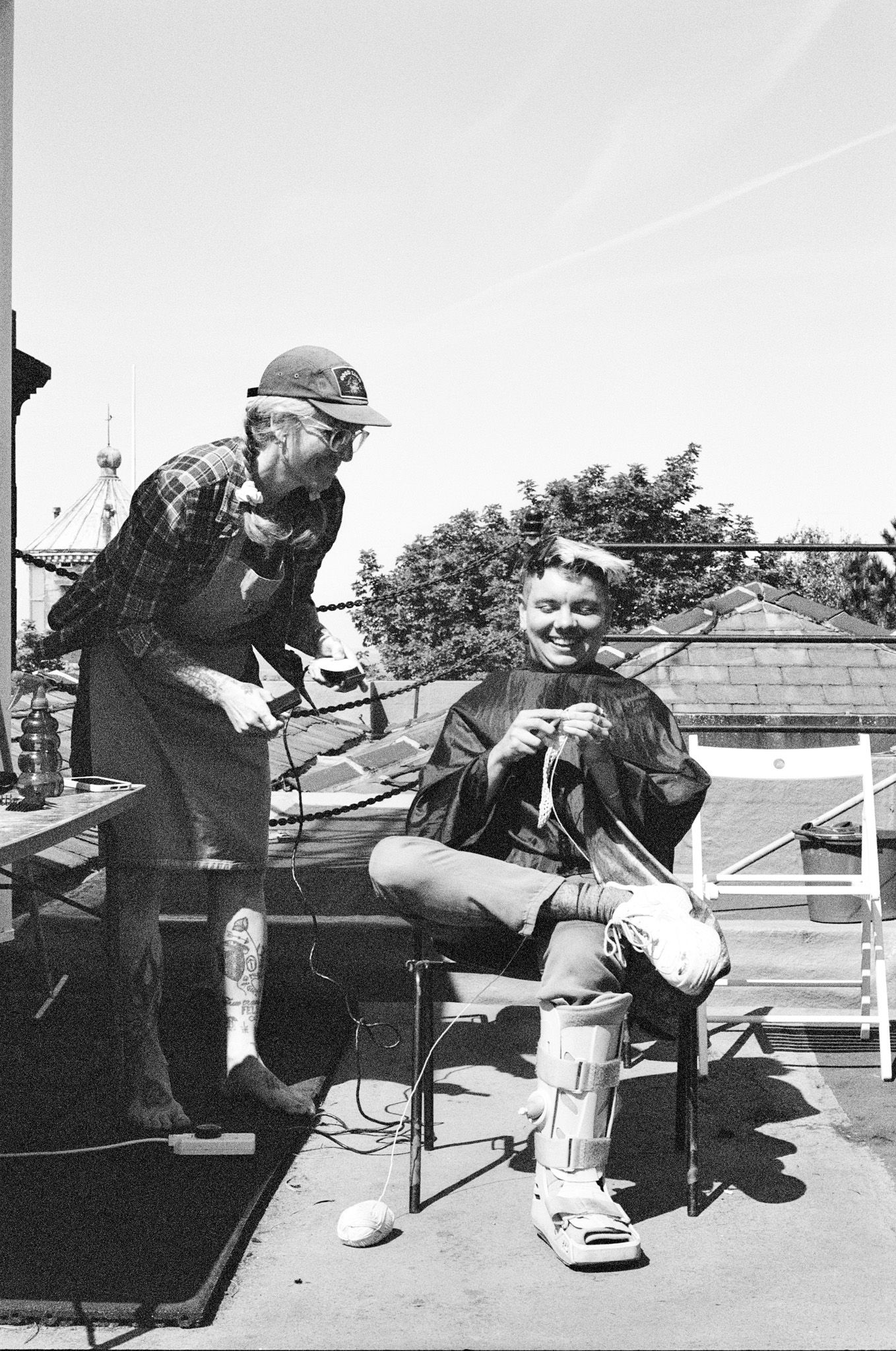 a woman cutting someone's hair on the rooftop, both smiling