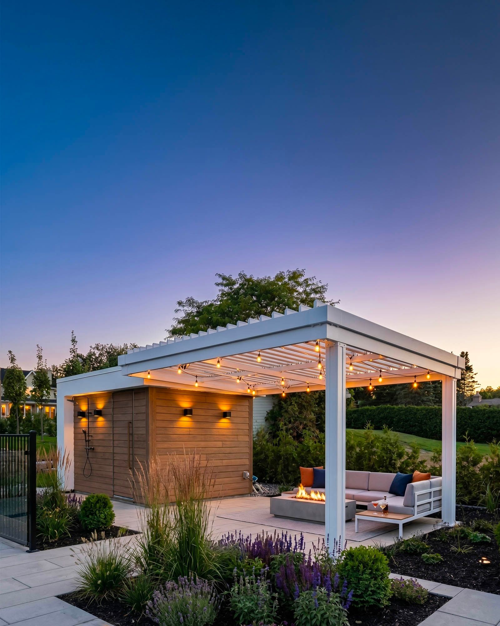 White SunLouvre Pergolas adjustable-louvre pergola at dusk with string lights, fire feature, and lounge seating