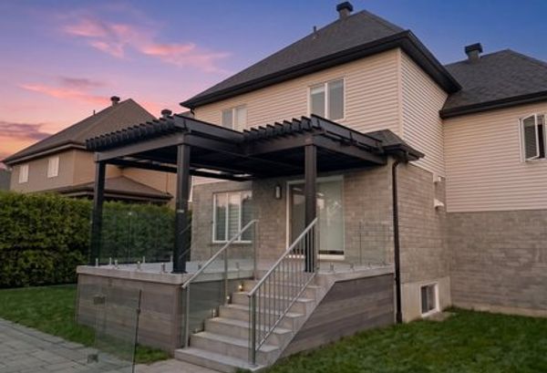 Black aluminum pergola on a glass-railed deck at sunset