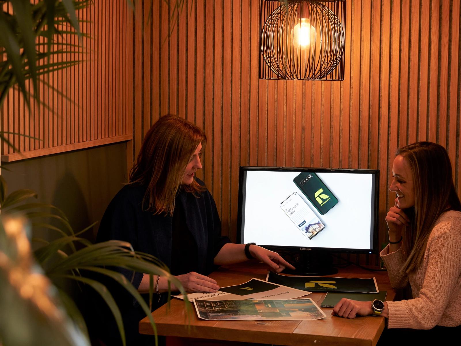 2 women looking at documents in a small office