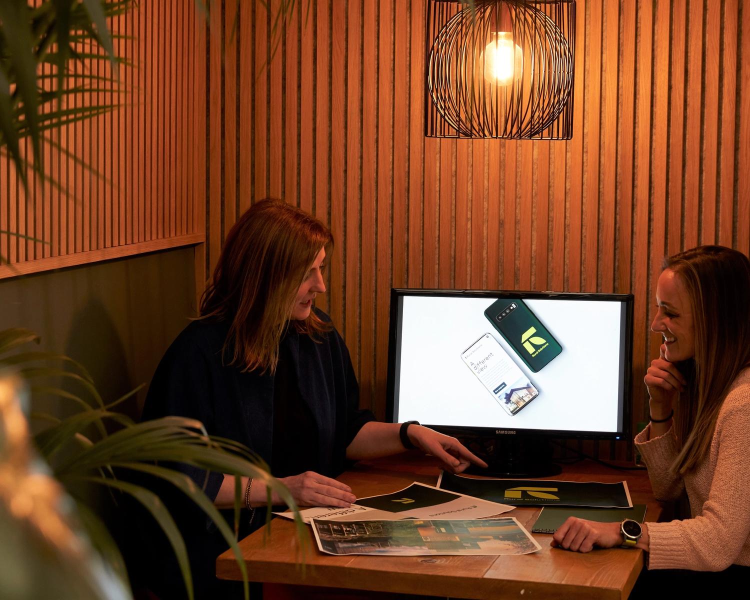 2 women looking at documents in a small office