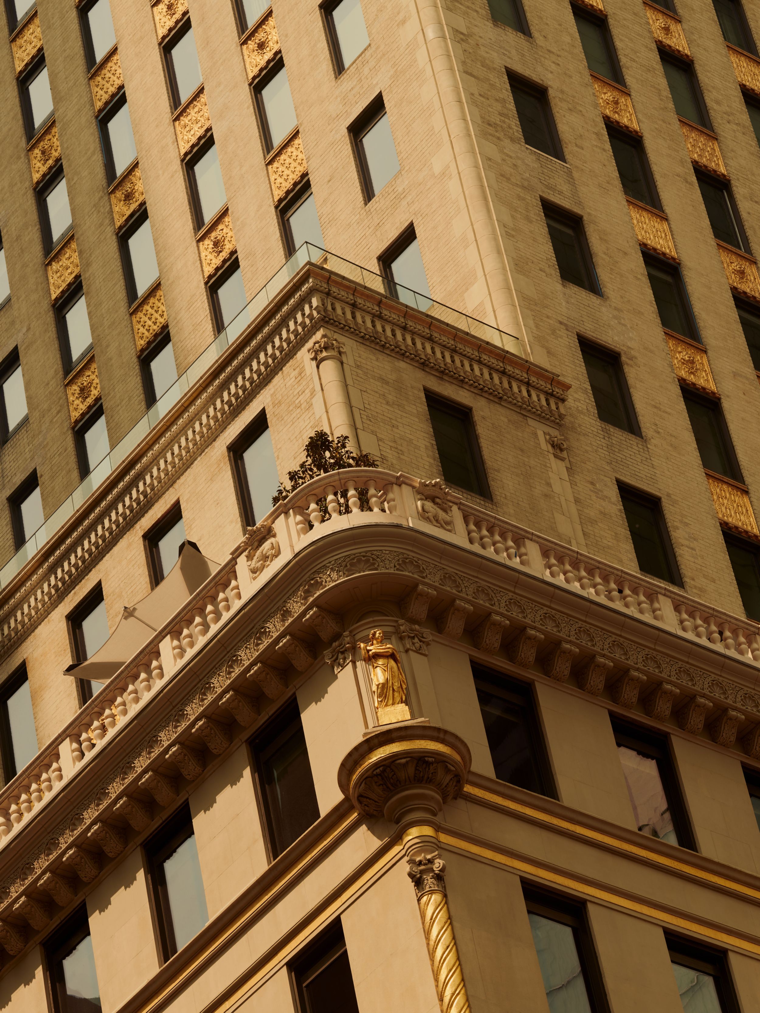 The proud and golden exterior of the Crown Building, restored to house Aman New York. Photographed by Robert Rieger.