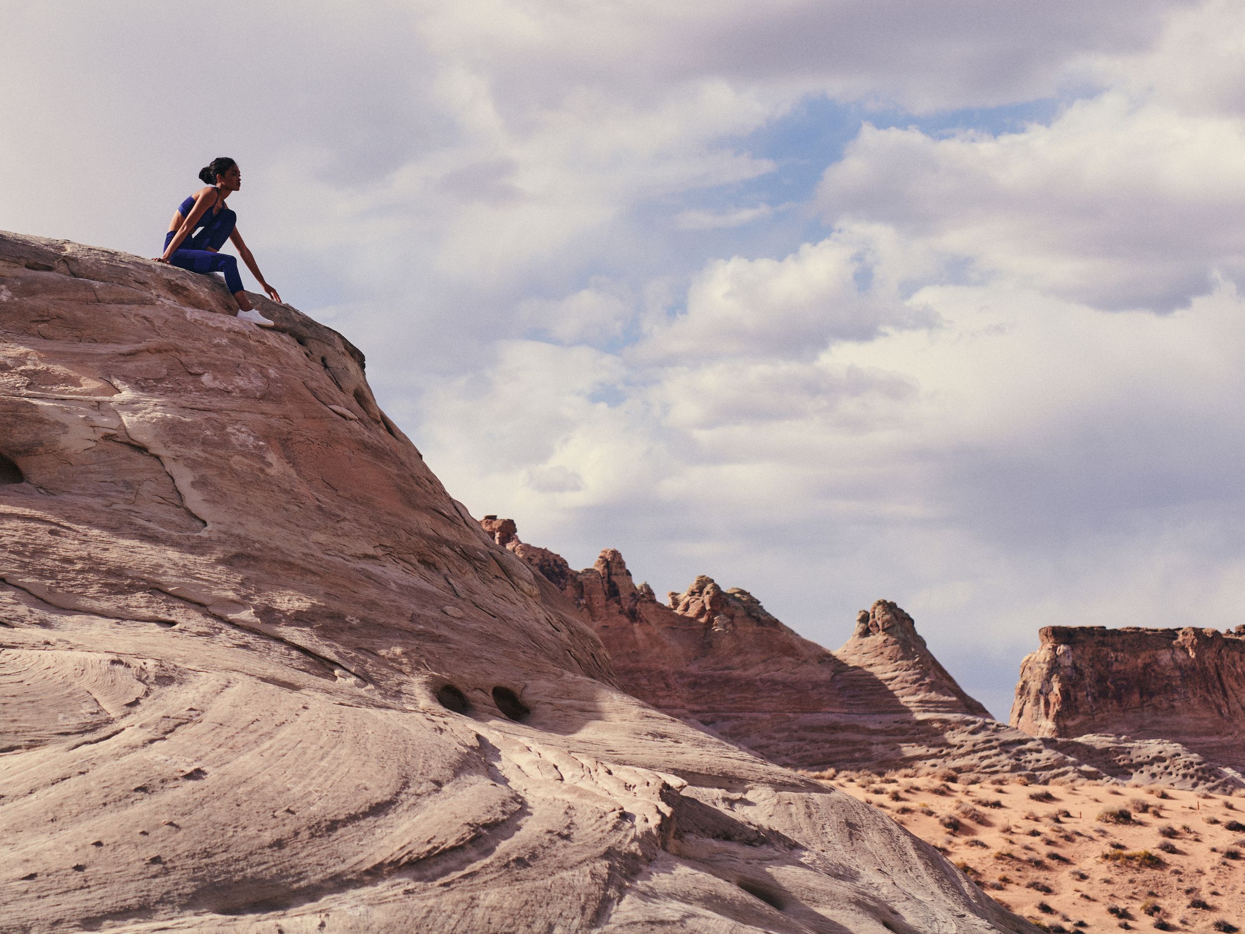 A model sits atop of a rock formation in the Utah desert. Photography by Chris Colls, Art Direction by Colville-Walker.