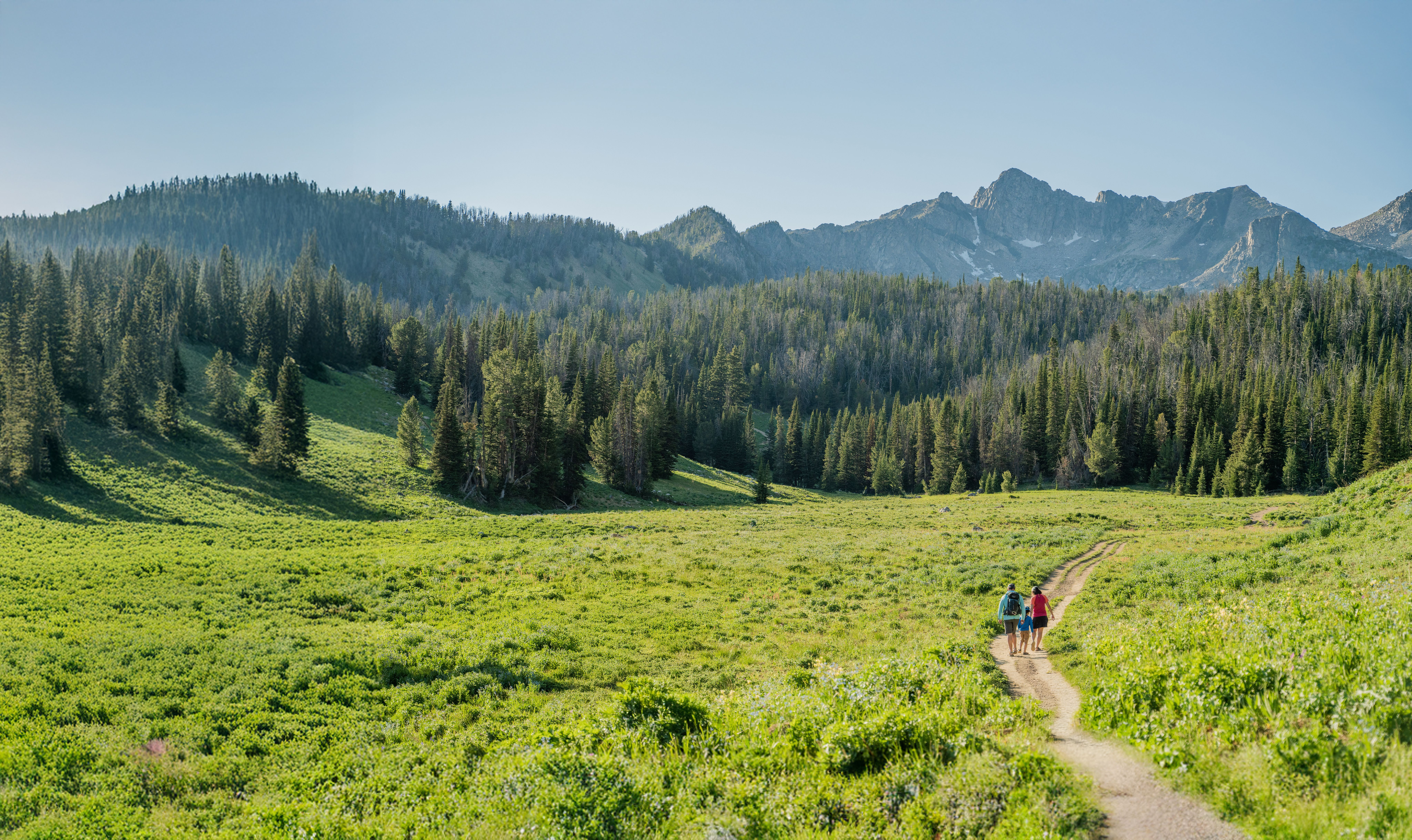 Two hikers walking down a path in the mountains