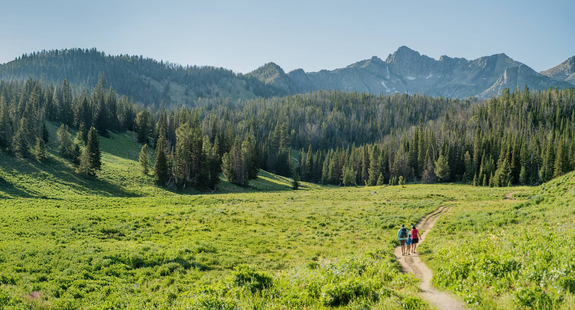 Two hikers walking down a path in the mountains