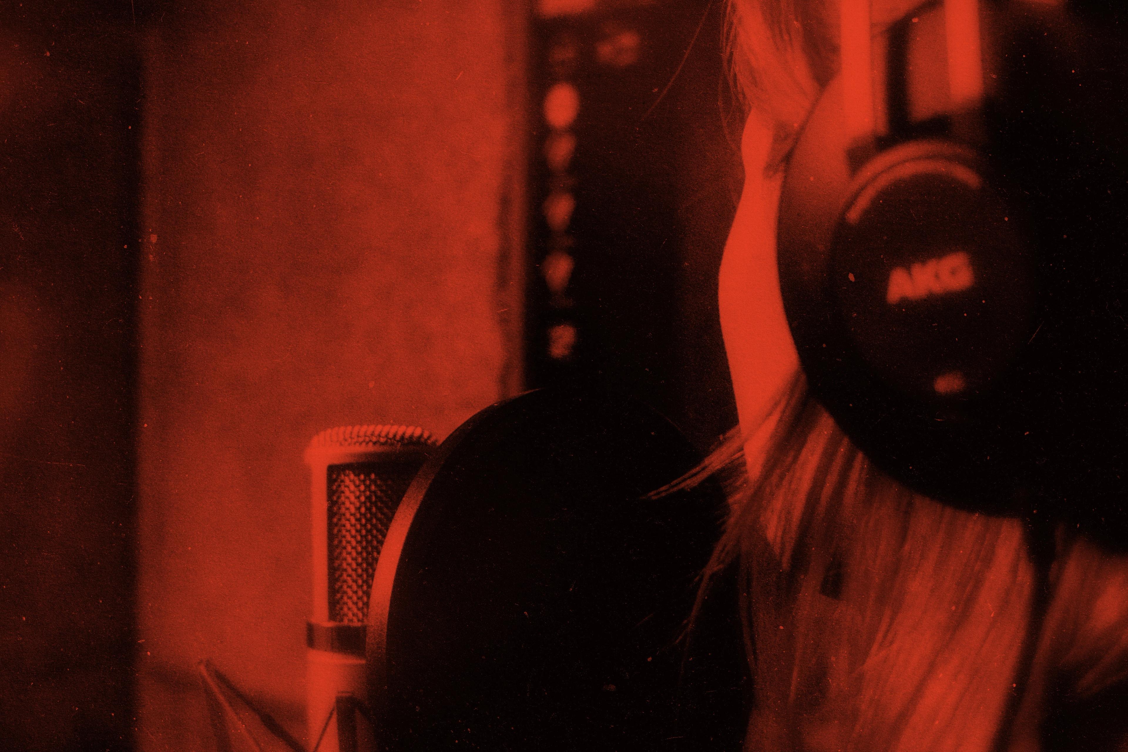 Podcast host earling headphones at microphone