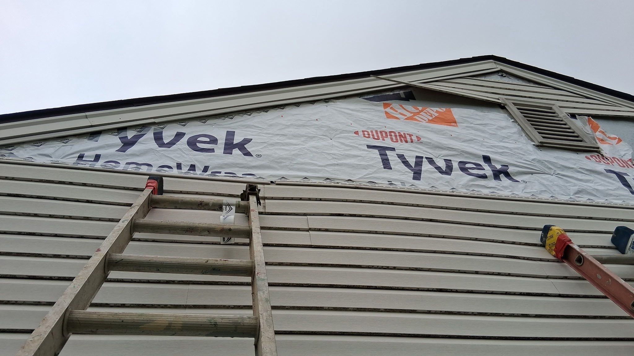 New siding going up over house wrap, with a ladder against the wall, Xenia, Ohio.