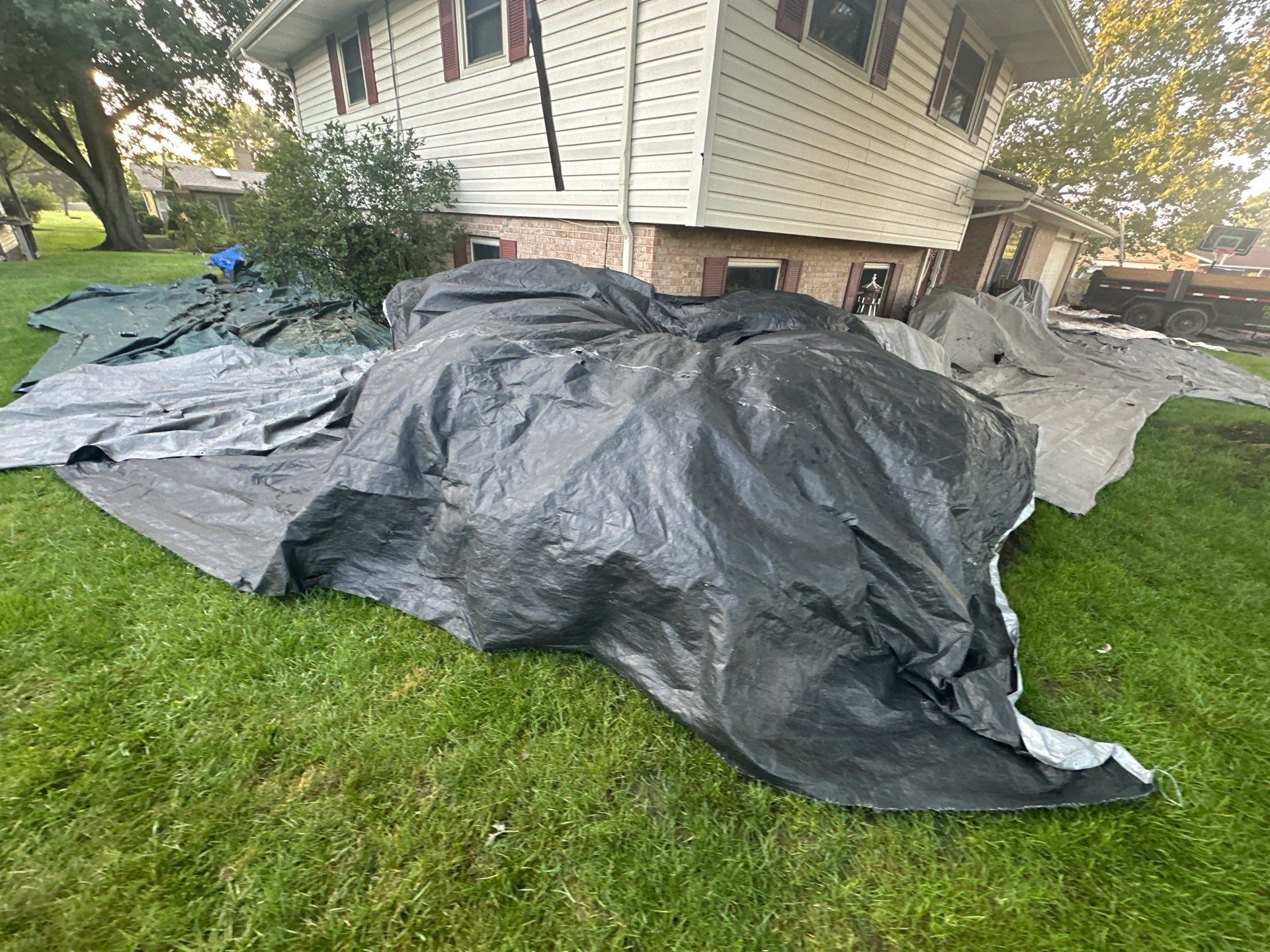 A dark tarp over a large shrub beside the two-story wing, Dayton, Ohio.