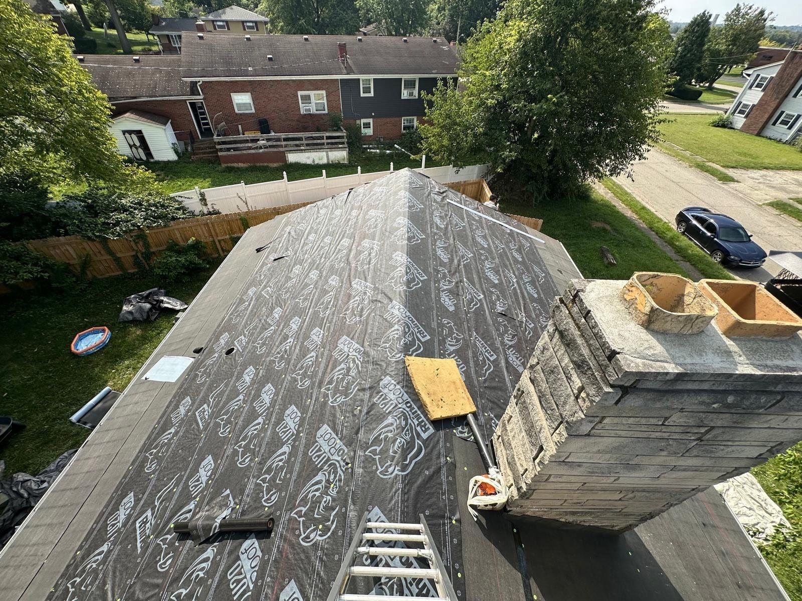 Synthetic underlayment over the hip roof beside the stone chimney, Fairborn, Ohio.