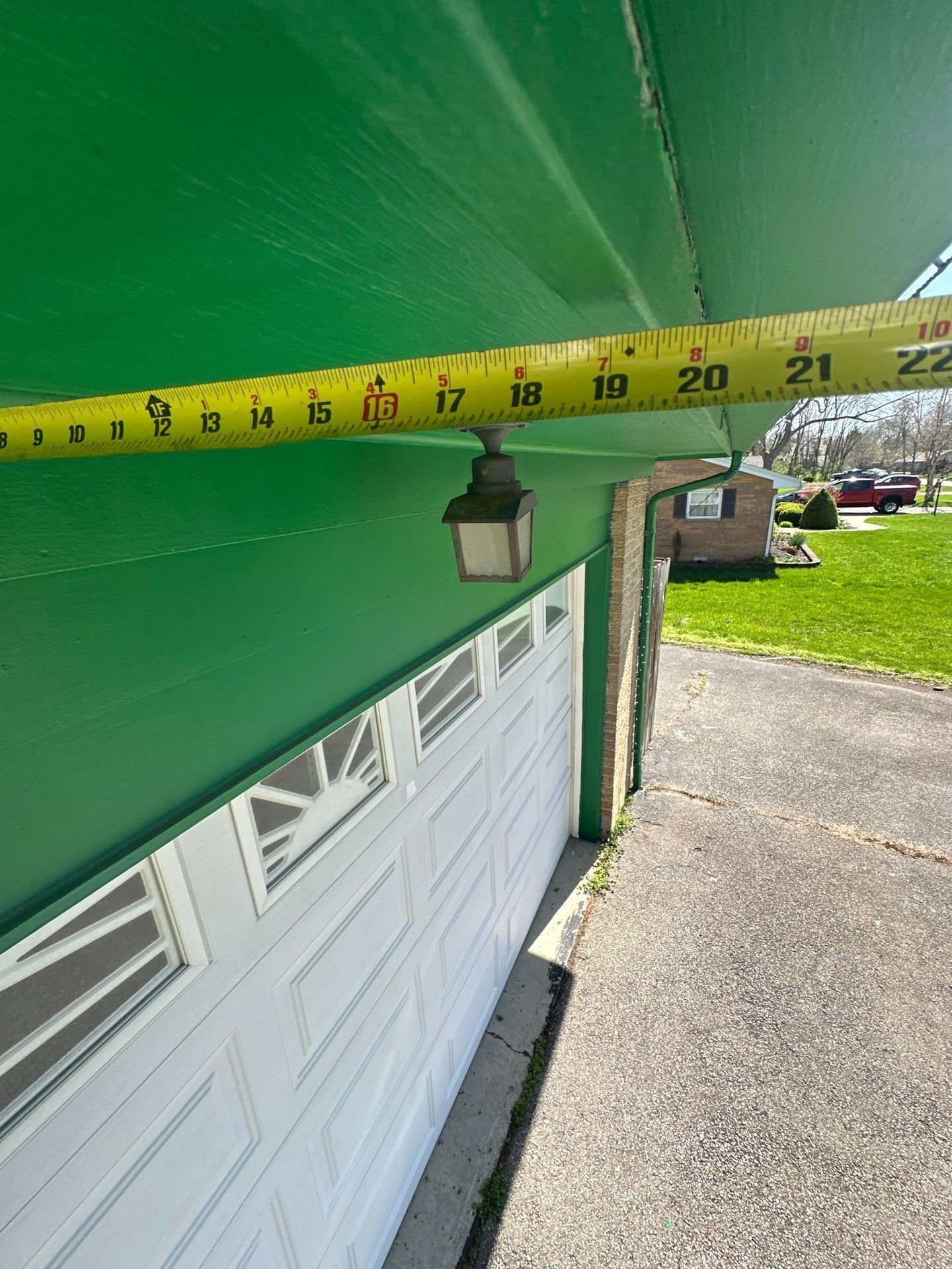 Tape measure stretched along the garage overhang to size the roof edge, Beavercreek, Ohio.