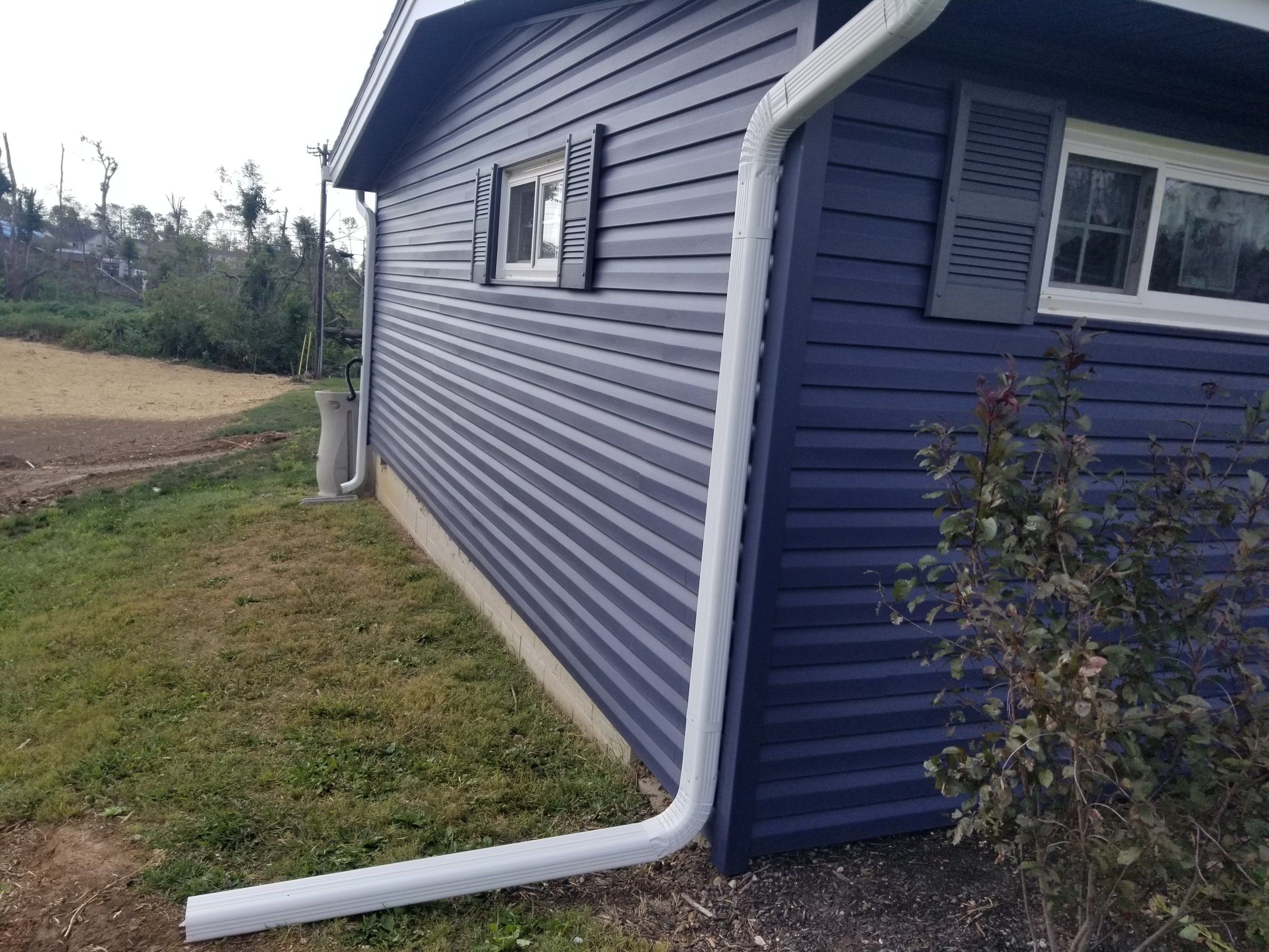 The side of the house in blue siding with a white downspout, Beavercreek, Ohio.