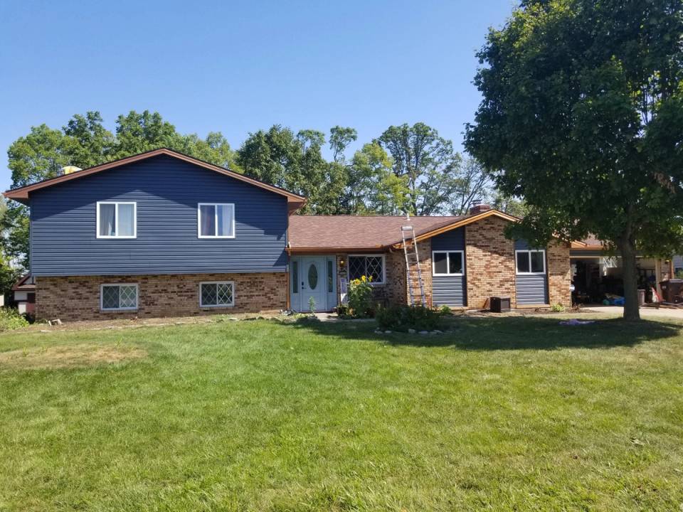 The finished house on Somerset Dr from the front lawn, in dark blue-gray siding with copper-colored trim, Beavercreek, Ohio.