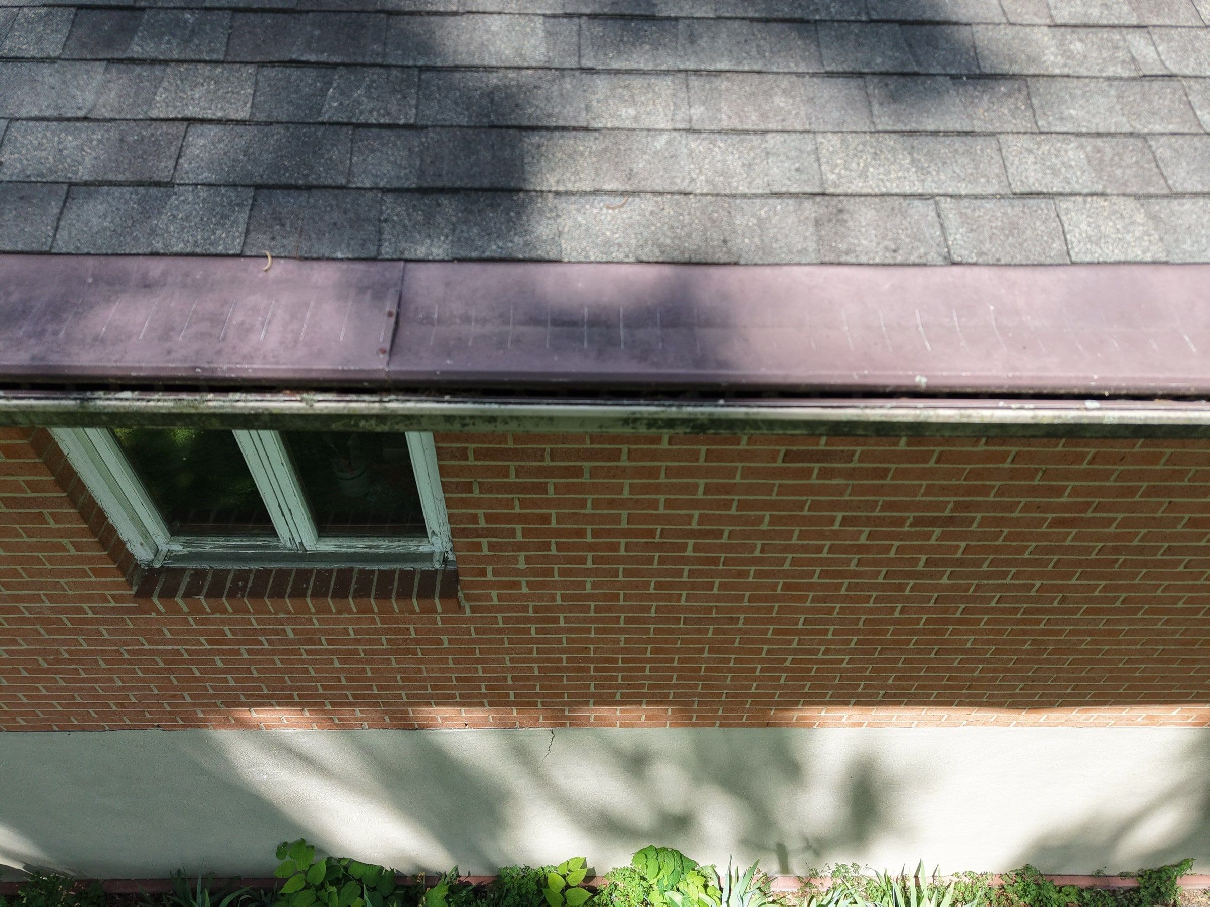 Shingles down to the roof edge above brick