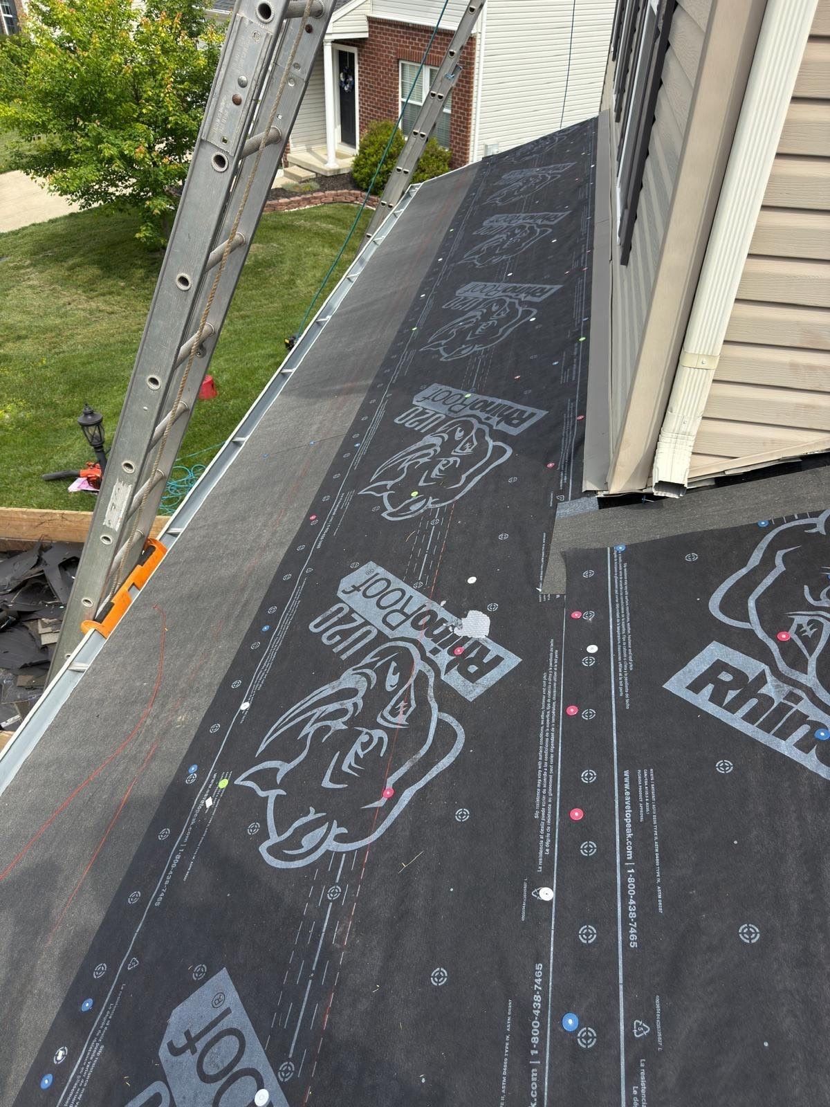 Synthetic underlayment on the low roof against the siding, with ladders at the edge, Beavercreek, Ohio.