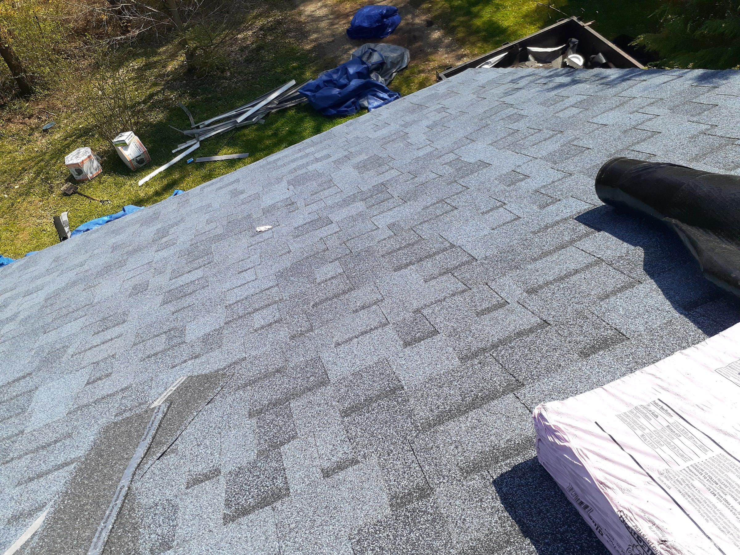 A roll of ridge vent and a bundle of ridge cap on the nearly finished slope, Yellow Springs, Ohio.