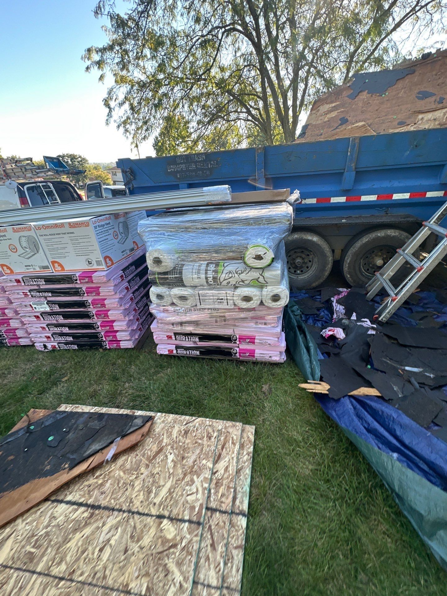 New OSB, shingle bundles and underlayment rolls beside the dump trailer, West Carrollton, Ohio.