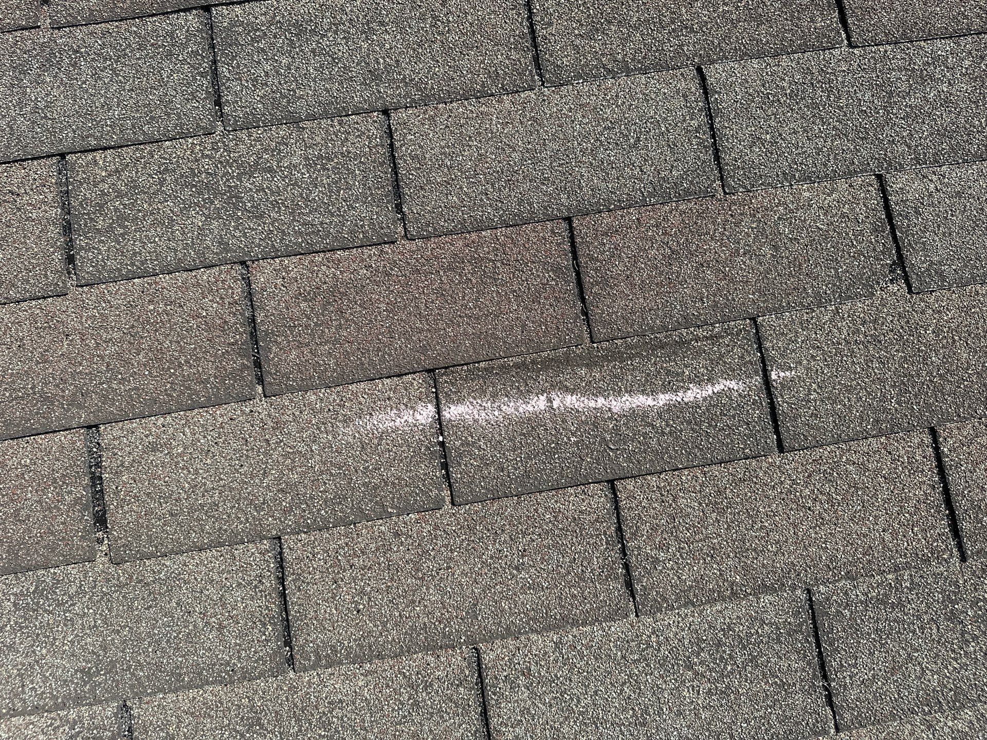 A chalk mark on a wind crease across the top of a shingle, Kettering, Ohio.