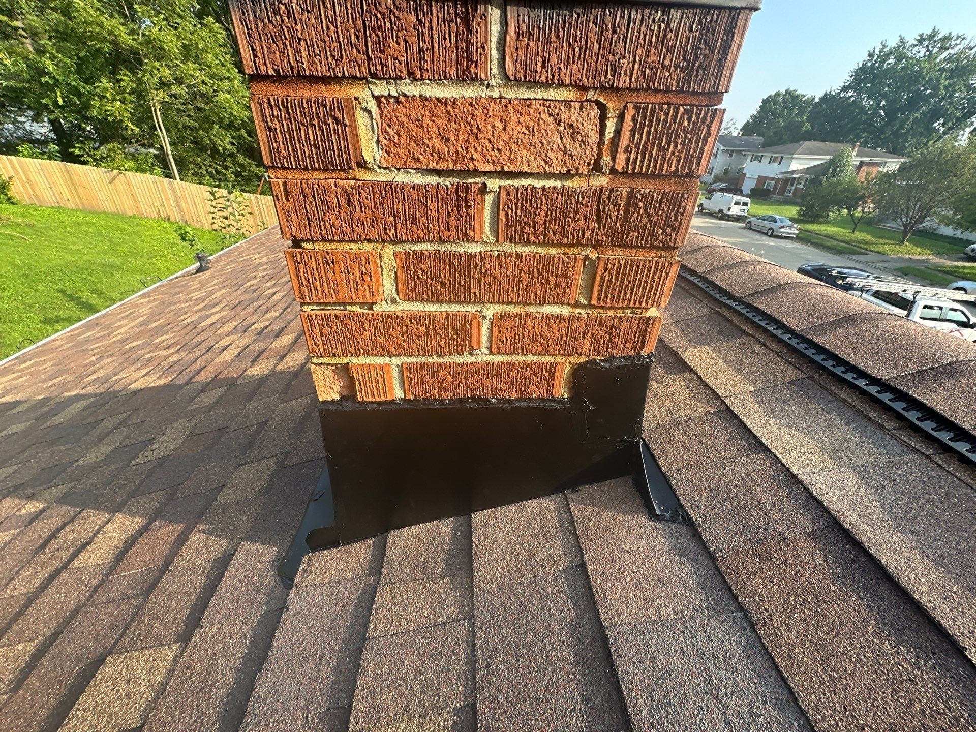 New black flashing at the base of the brick chimney on the finished roof, Fairborn, Ohio.