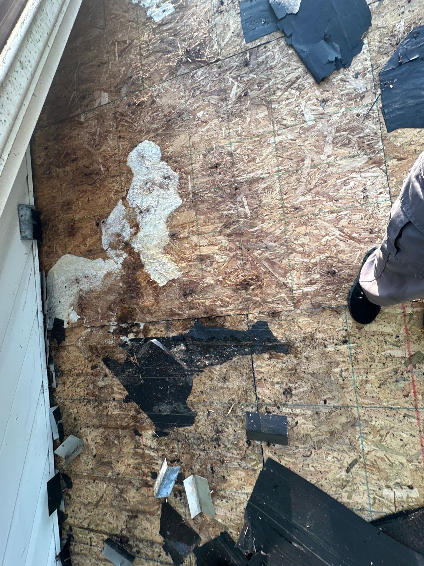 Water-stained deck boards at the eave beside the wall, after tear-off, Dayton, Ohio.