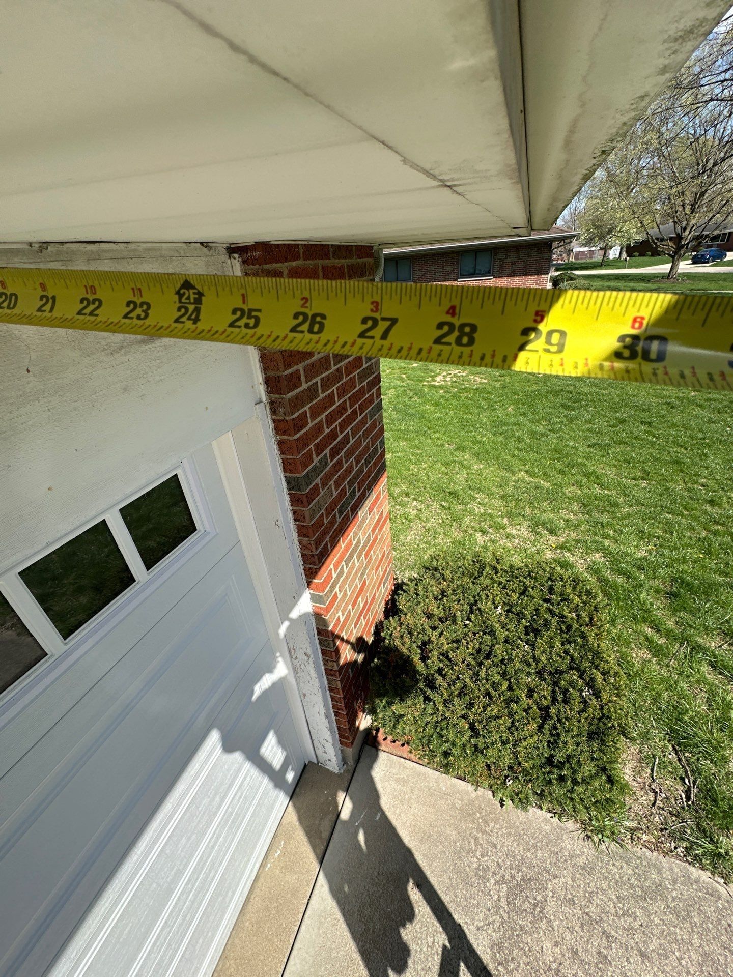 Tape measure held across the garage eave overhang during the inspection, Beavercreek, Ohio.