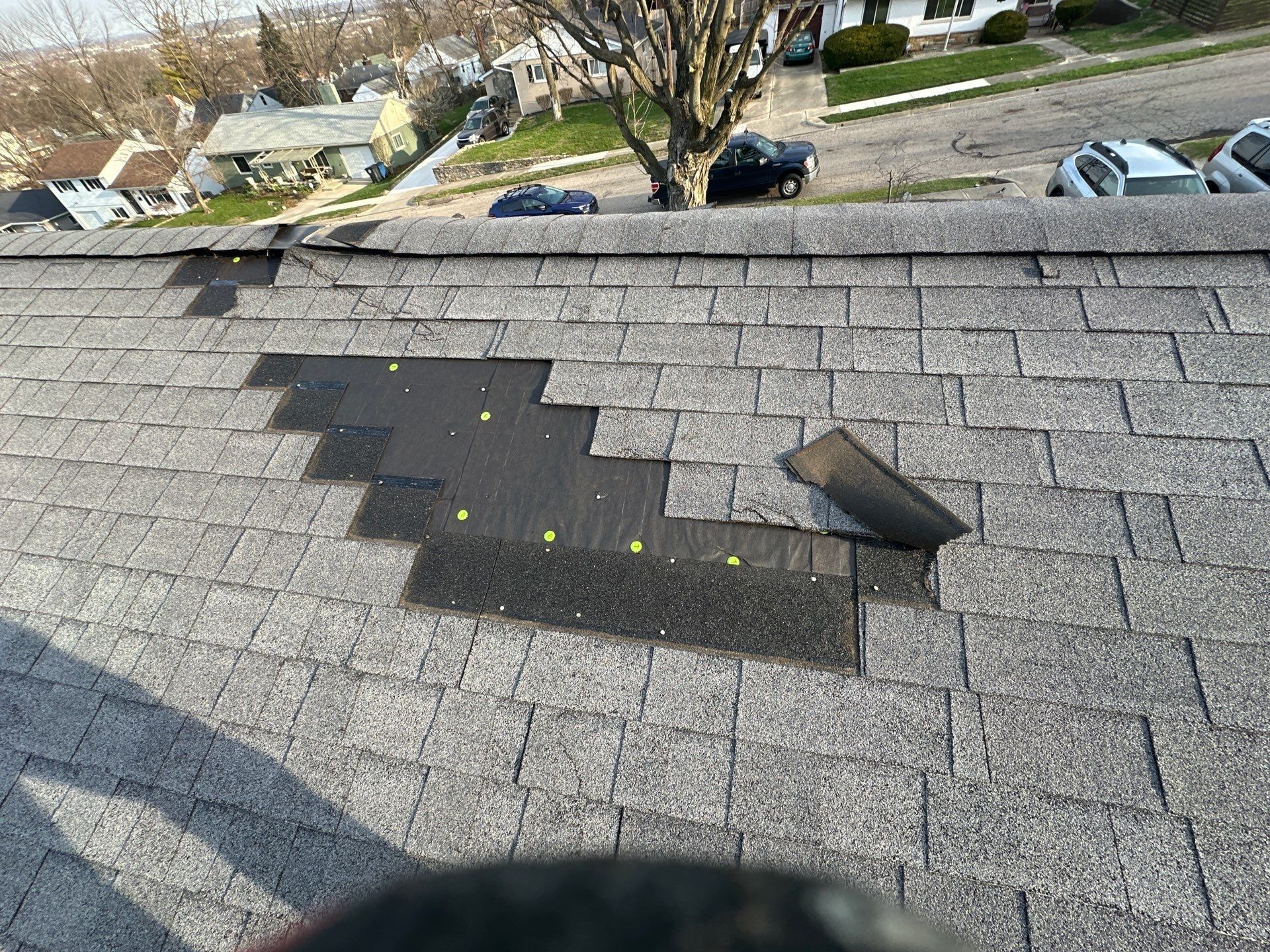 Storm-torn shingles and a stepped patch on the old roof above the street, Dayton, Ohio.