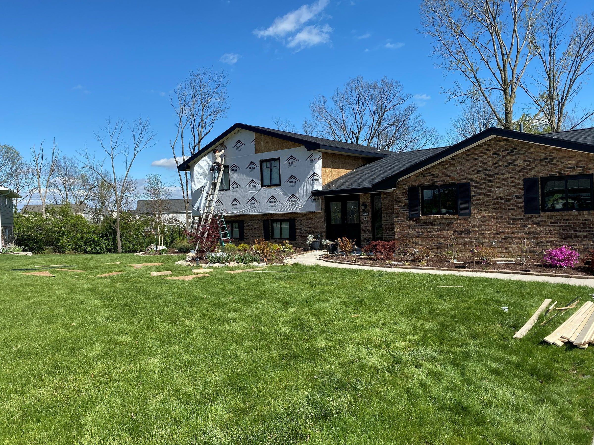 House wrap going on the front of the upper story, seen across the lawn, Beavercreek, Ohio.