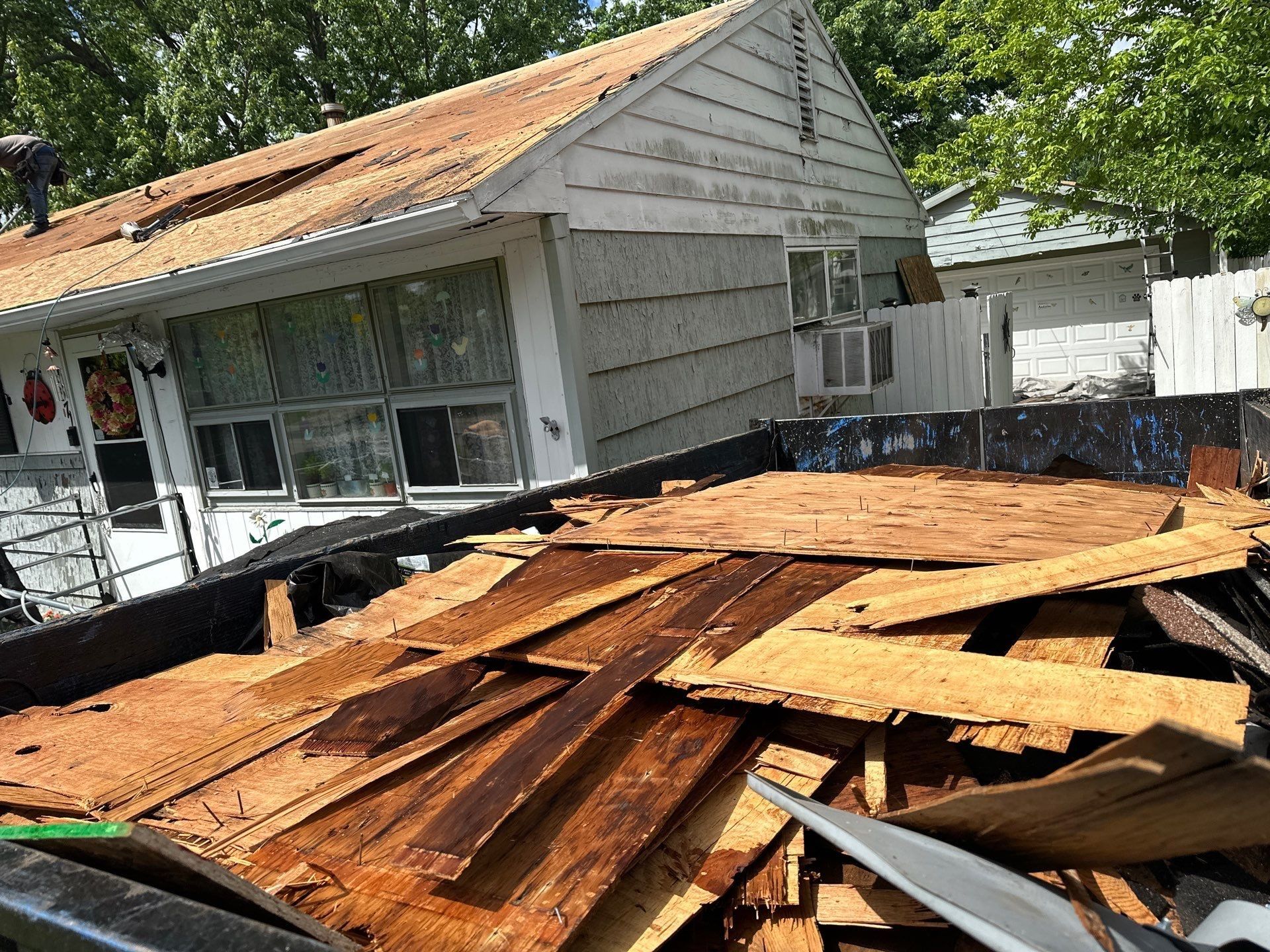 The old roof sheathing piled in the dumpster beside the house, Dayton, Ohio.