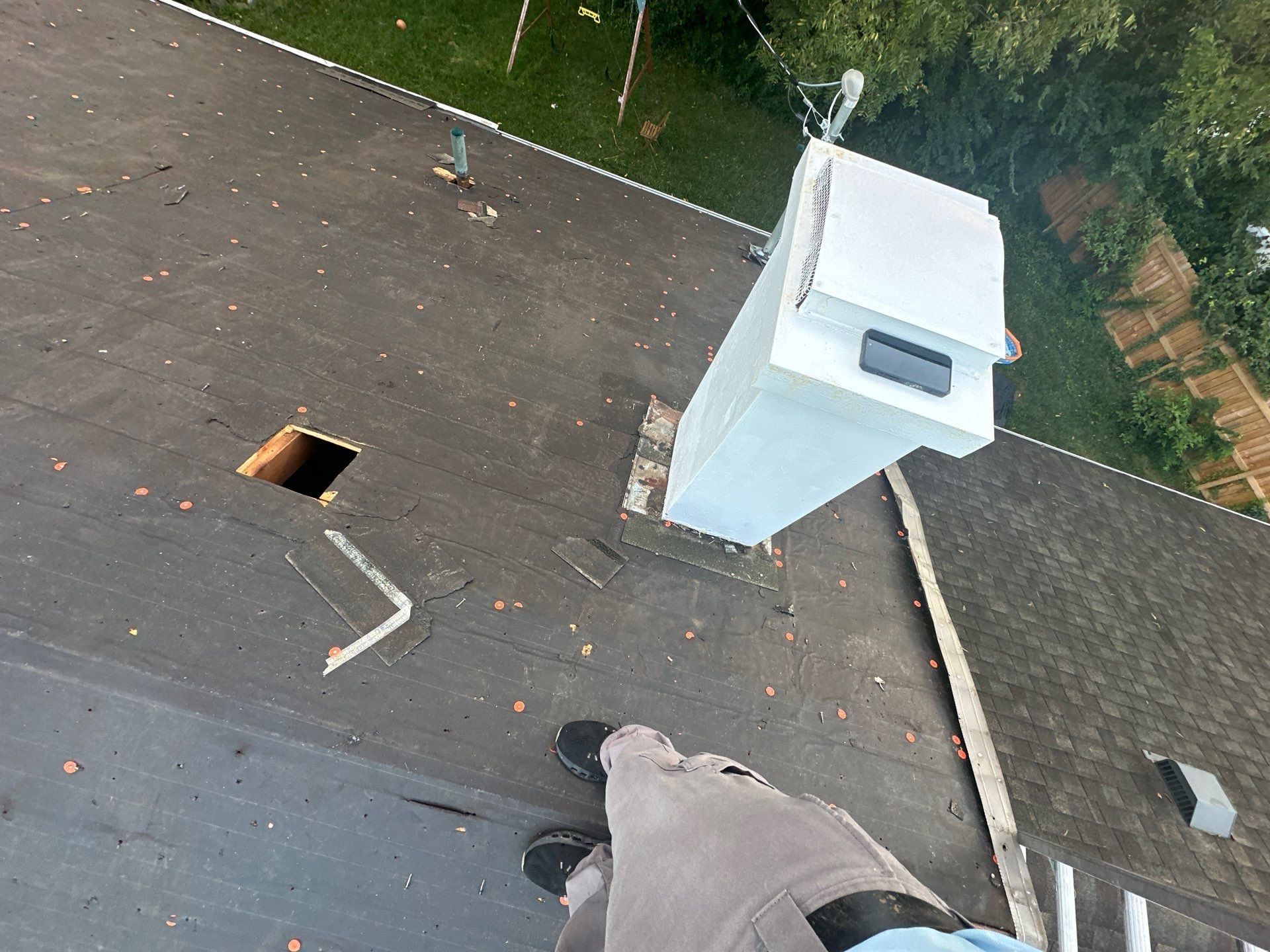 Tear-off starting near the white chimney chase, with an open vent hole in the deck, Fairborn, Ohio.