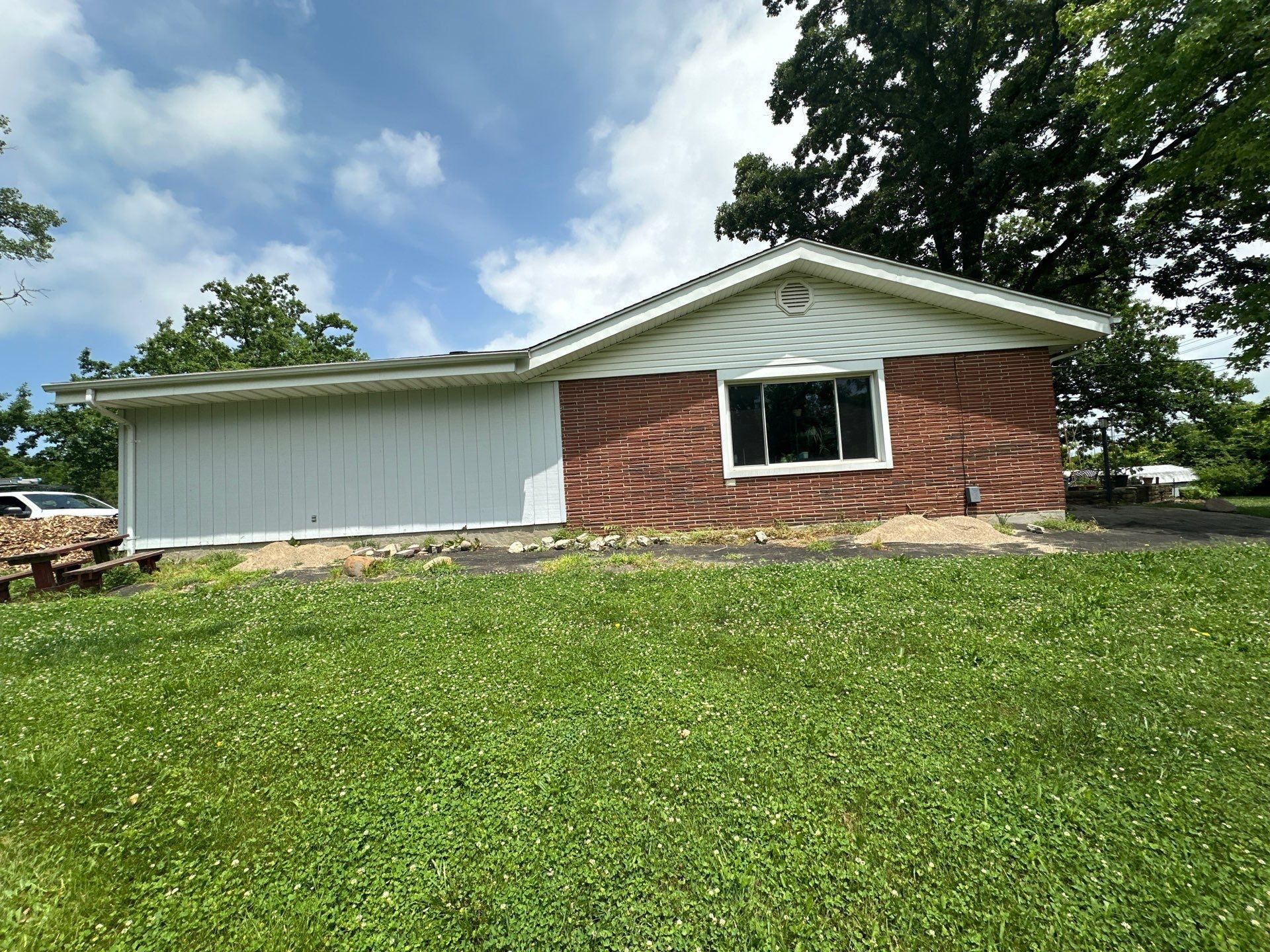 The white-sided garage wall under its old gutter, seen from the side yard.