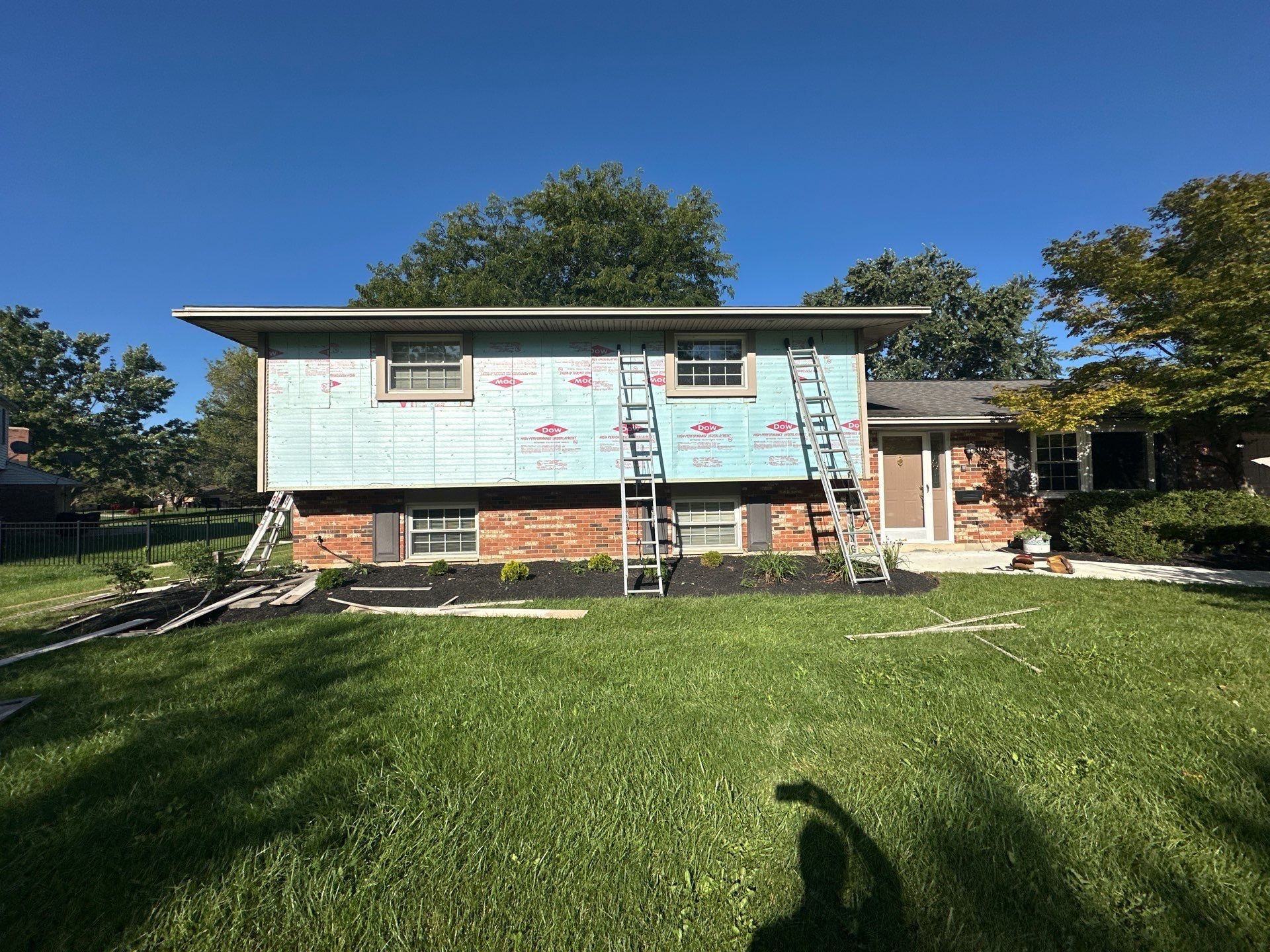 The back of the house wrapped, with ladders against the wall, Beavercreek, Ohio.