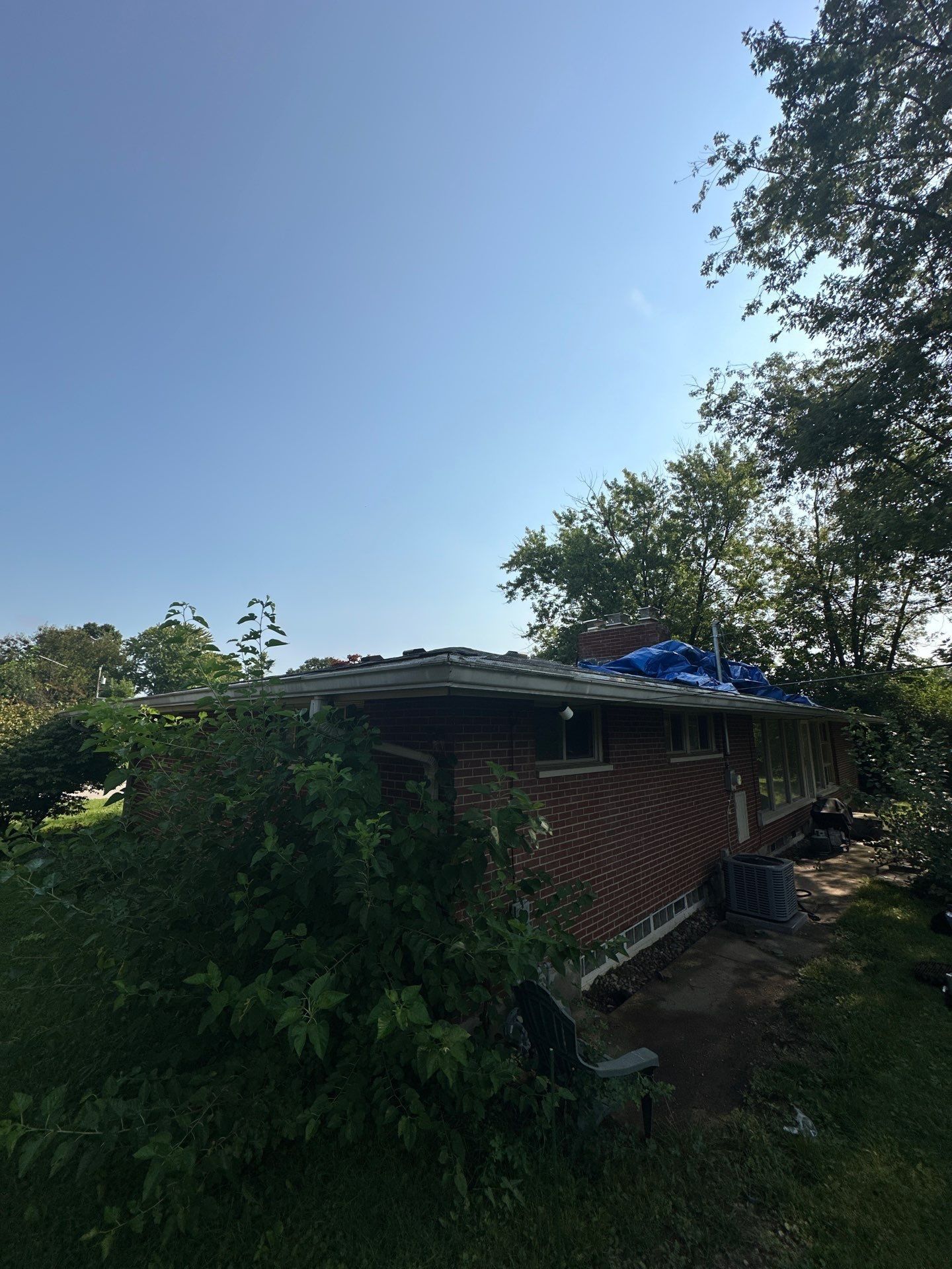 A blue tarp visible on the back of the roof from the yard, Kettering, Ohio.