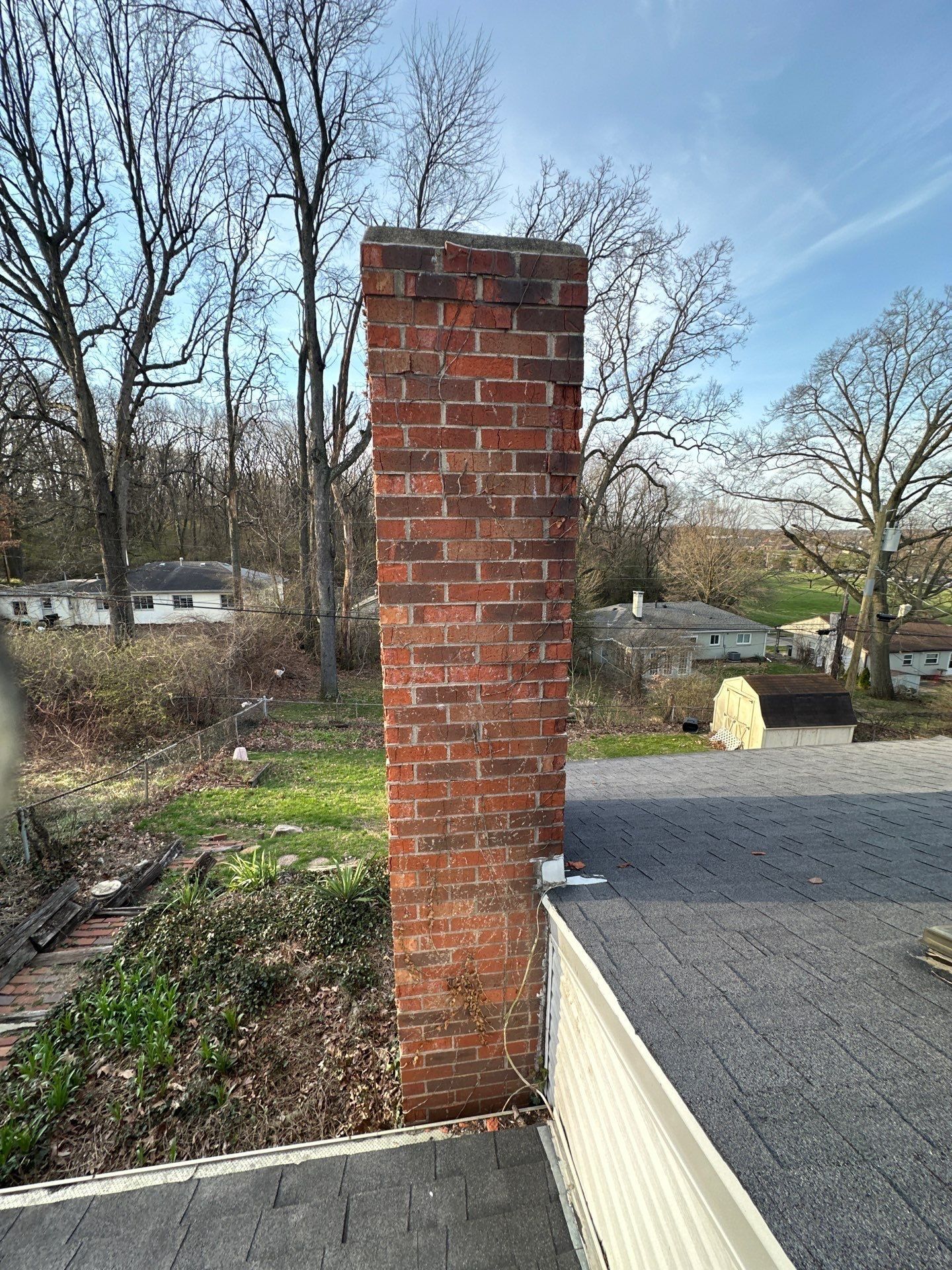 Tall brick chimney against bare trees