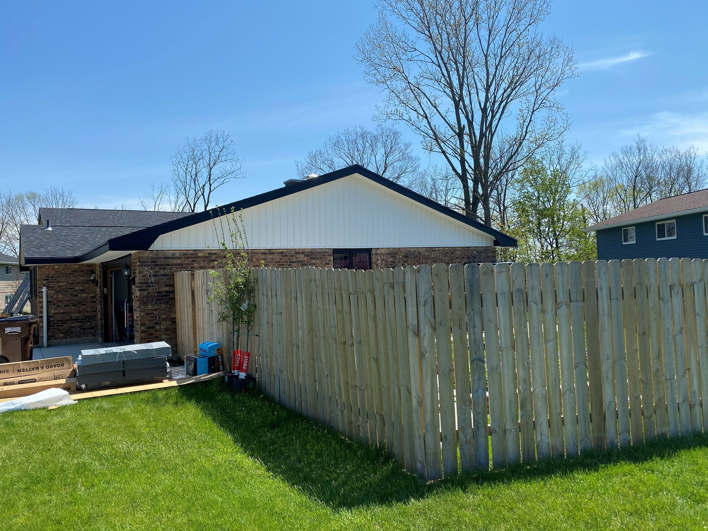 The brick wing gable in new white siding, seen past the fence, Beavercreek, Ohio.