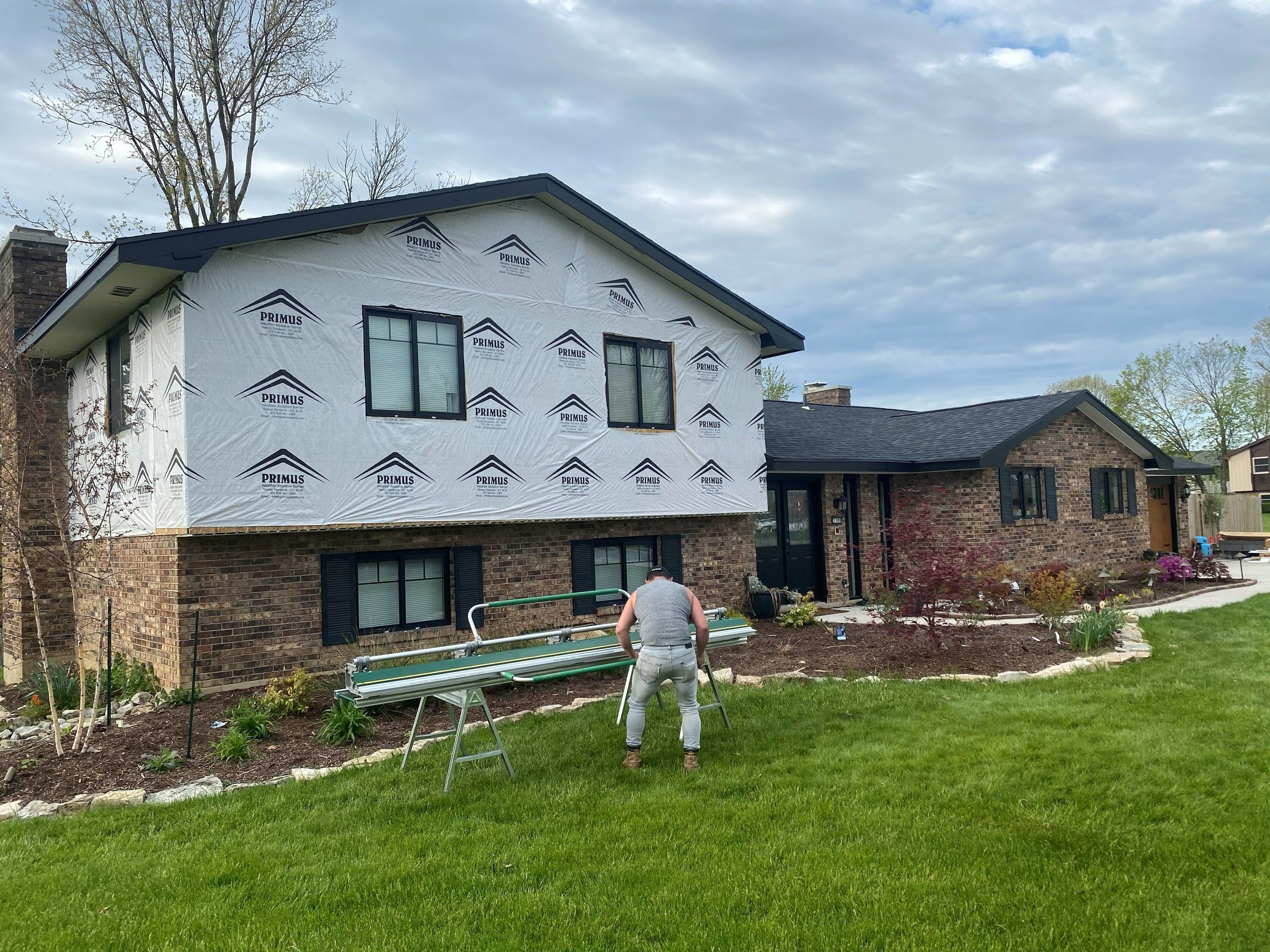 The wrapped side of the house, with a crew member bending trim on the lawn, Beavercreek, Ohio.