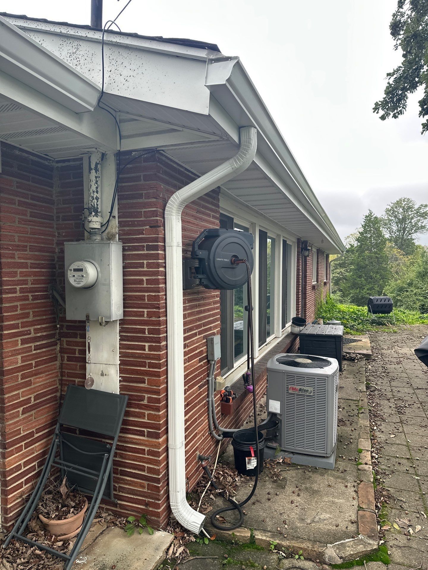 A new downspout beside the electric meter and the air conditioner at the back of the house.